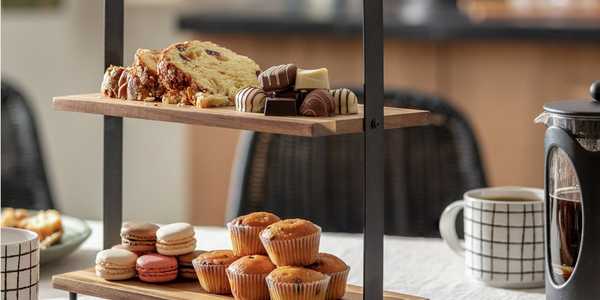 Habitat 2 tier metal and wood serve board with cupcakes and chocolates on it.